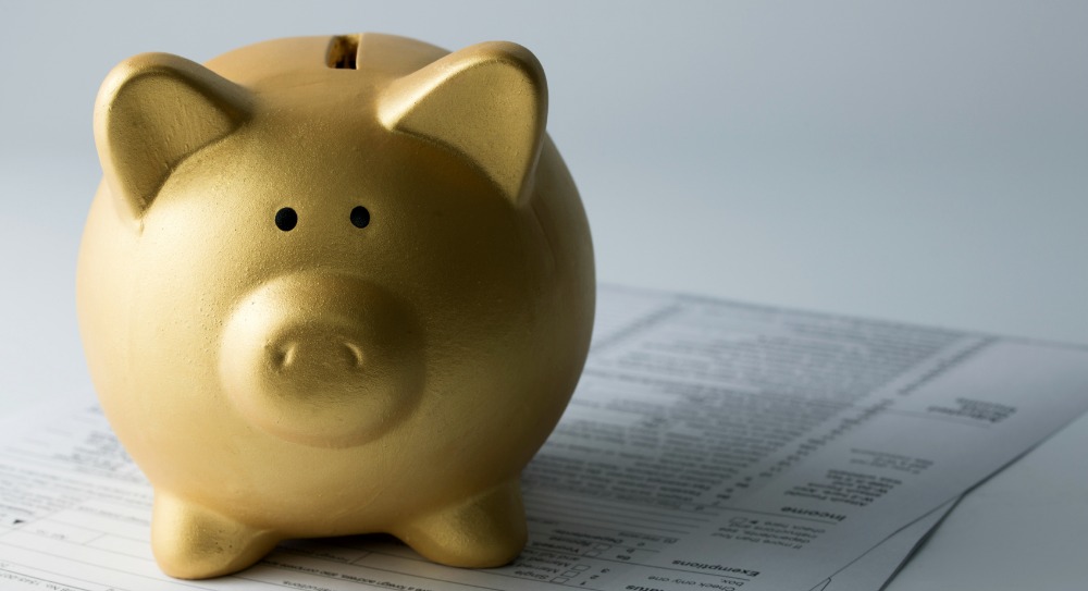 Golden piggy bank sitting on income tax form